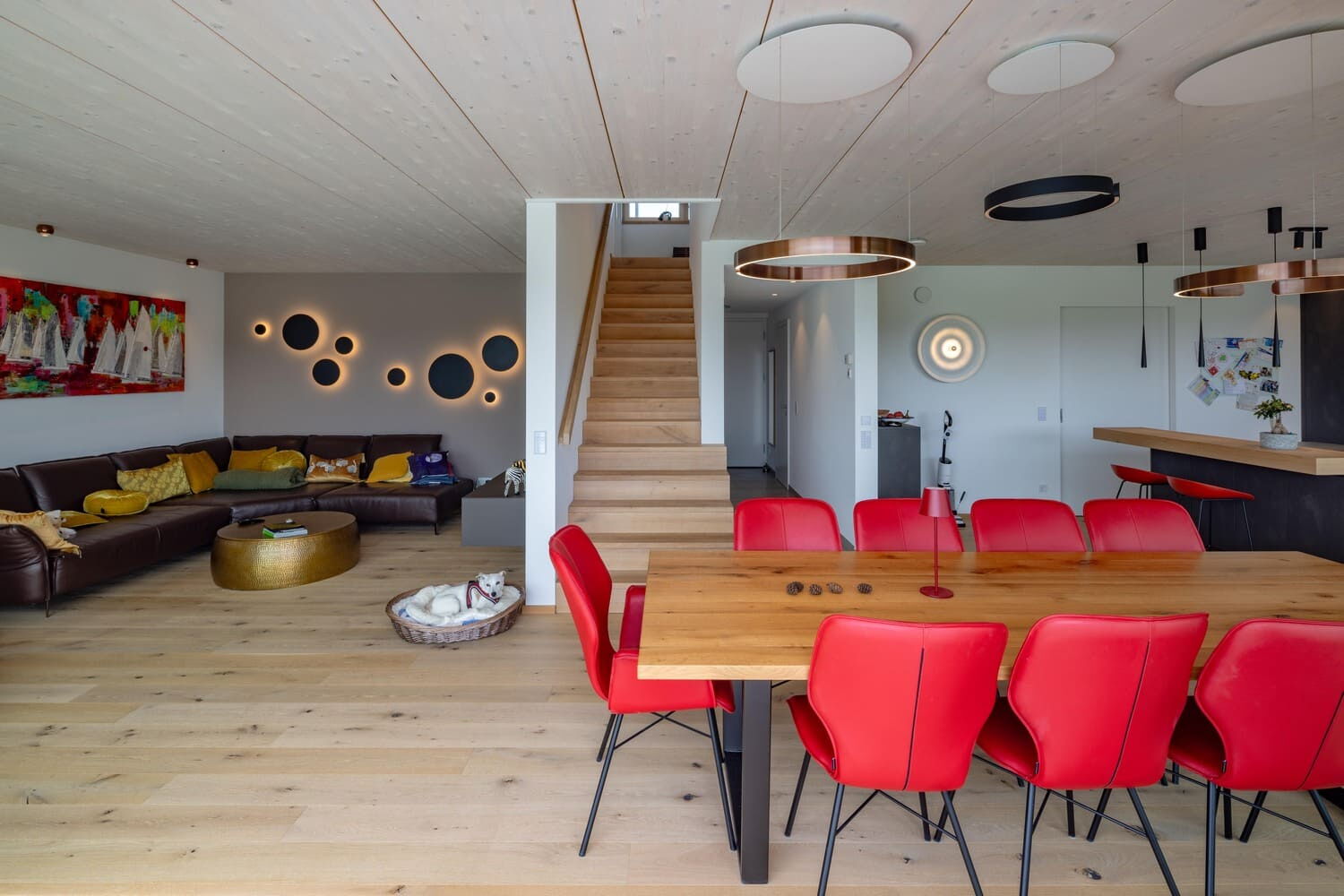 verputztes Holzhaus in Weilheim, Einblick in Wohn-Esszimmerbereich mit Treppenaufgang, weiße Sicht-Holzdecke