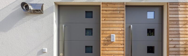 Zwei moderne Eingangstüren mit den Hausnummern 13 und 13a, umgeben von Holz- und Putzfassade. | © Name