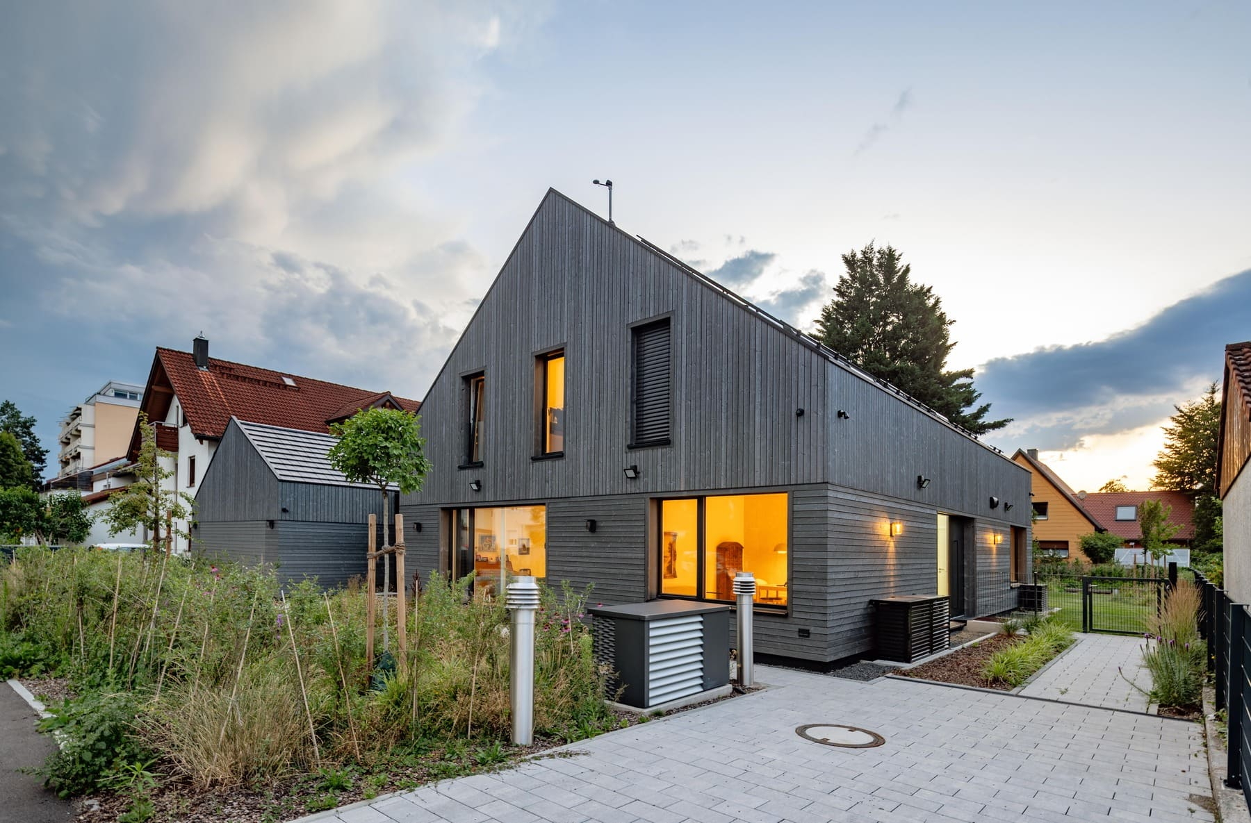 Ein modernes Holzhaus mit großen Fenstern und einem gepflegten Garten, umgeben von einer ruhigen Nachbarschaft.