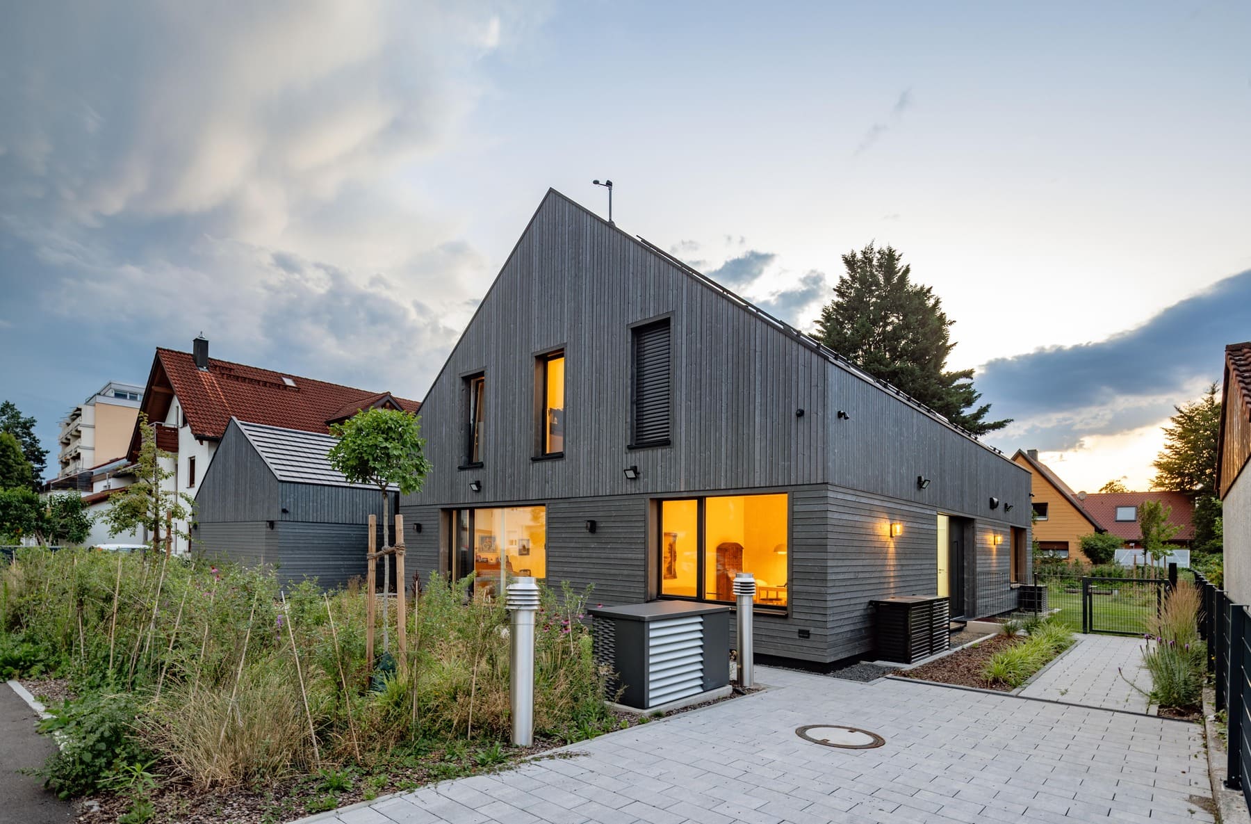Ein modernes Holzhaus mit großen Fenstern und einem gepflegten Garten, umgeben von einer ruhigen Nachbarschaft.