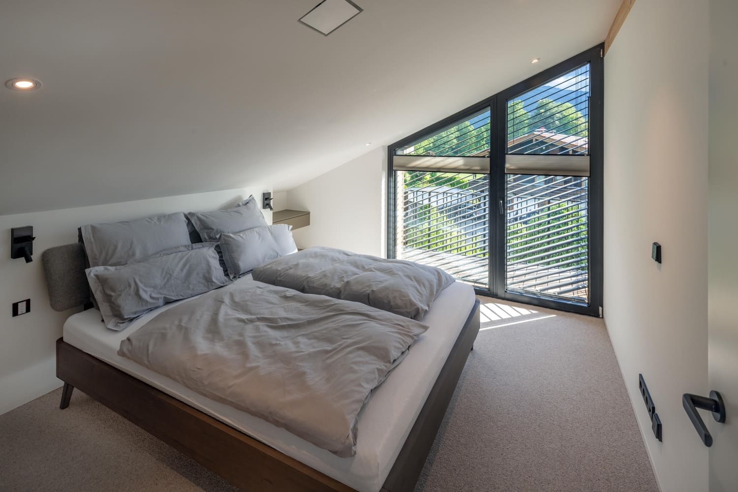 Gemütliches Schlafzimmer mit großen Fenstern, Holzmöbeln und modernen Akzenten in einem modernen, hellen Raum.